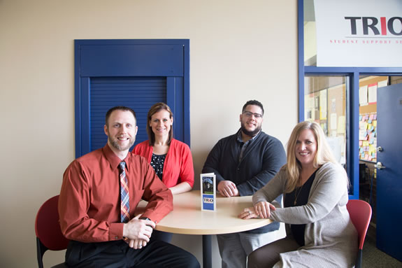 TRIO staff sitting at a round tan table facing forward.